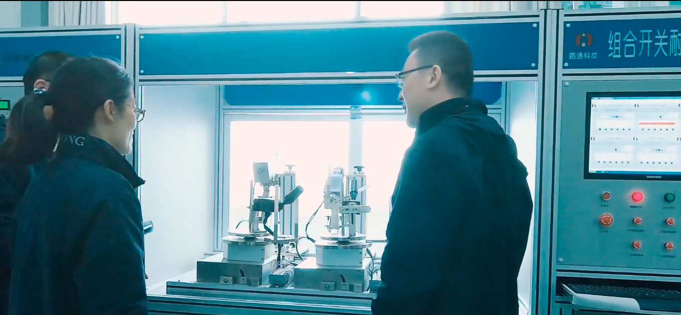 Dois homens e uma mulher conversando enquanto observam uma máquina de precisão