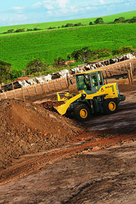 Cargadora SDLG LG918 que transporta tierra en el fondo vegetación verde