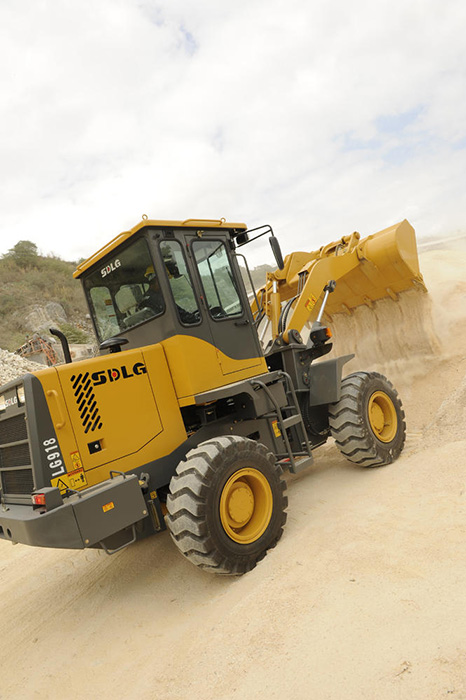 Cargador SDLG LG918 descargando piedras, en la montaña de fondo con vegetación