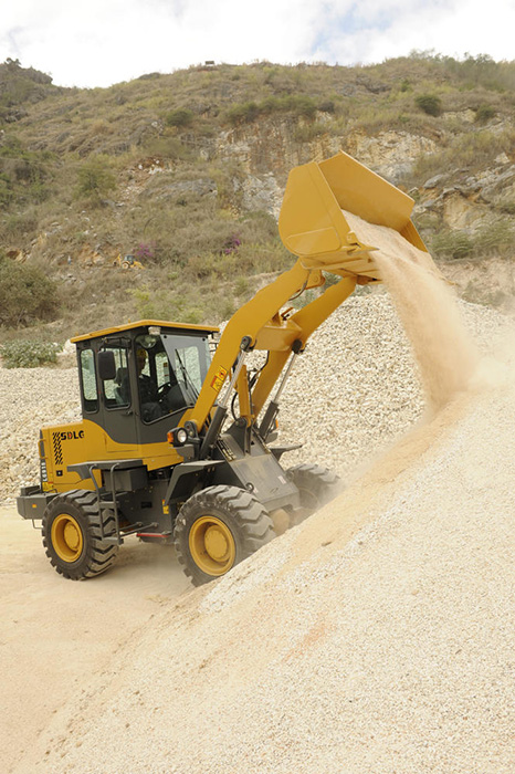 Cargador SDLG LG918 descargando piedras, en la montaña de fondo con vegetación