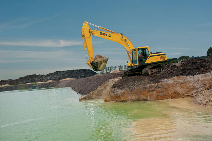 Excavadora SDLG LG6250E, al borde de un río, cargando tierra.