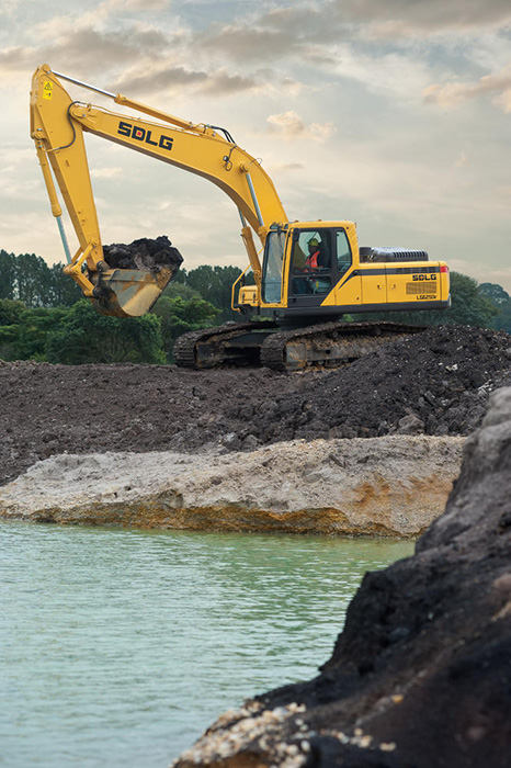 Excavadora SDLG LG6250E, al borde de un río, cargando tierra.