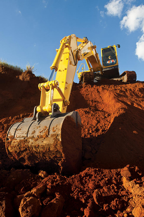 Excavadora en la cima de una colina, excavando la tierra desde la parte más baja.