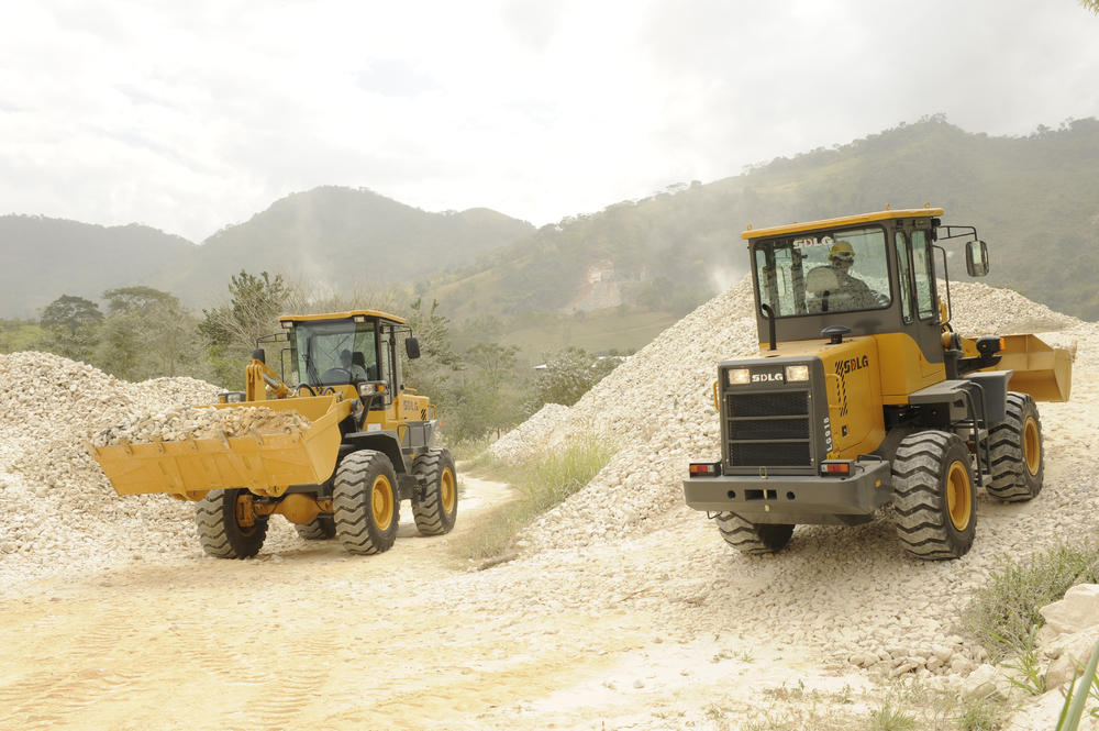 Dos cargadores SDLG que transportan piedra de una cantera em el fondo de las montanãs