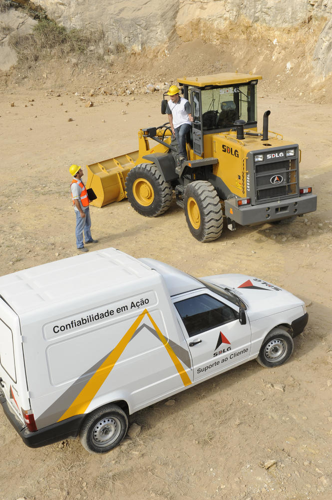 Um coche de atención al cliente blanco, al fondo un trabajador está dentro del cargador hablando con outro trabajador que está parado a un lado.