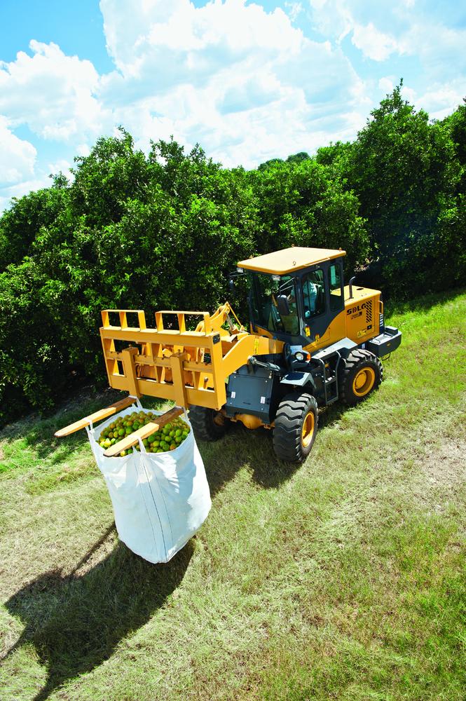 Imagen aérea de una cargadora recogiendo naranjas en medio de la plantación