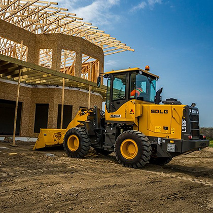 Cargadora de ruedas SDLG L918F, frente a una casa en construcción.