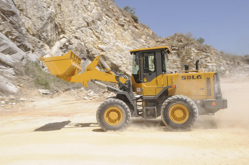 Cargadora de ruedas LG936L SDLG transportando piedras, un muro de piedra al fondo