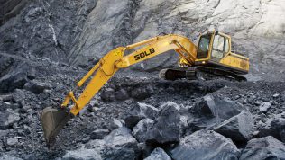 Excavadora SDLG, excavando en una cantera, con el brazo de la máquina bien extendido, al fondo una pared de rocas.