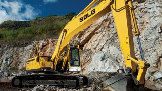 Excavadora SDLG, quitando tierra del suelo, al fondo una pared de rocas.