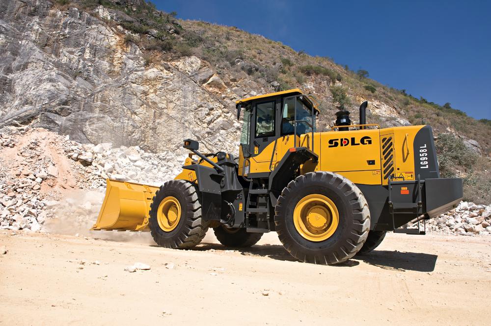 Cargadora SDLG modelo LG958L, cargando rocas, al fondo una pared de rocas.