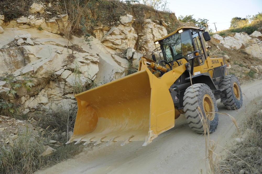 Cargadora SDLG, vacía, al fondo algunas rocas y vegetación baja.