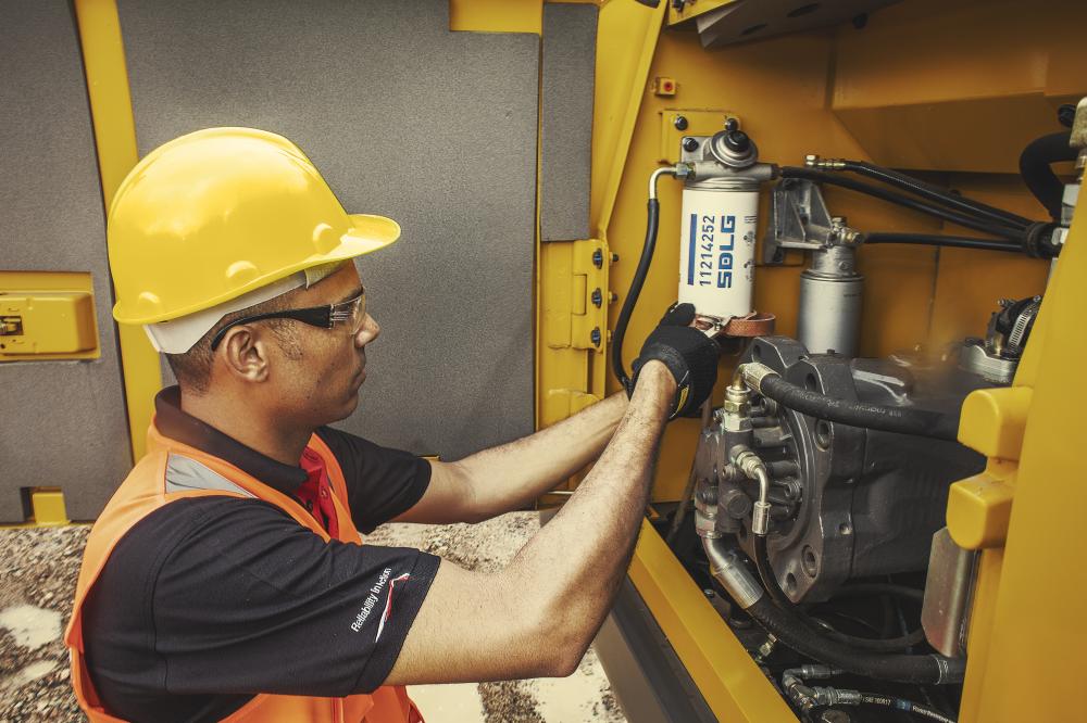 Um homem usando colete laranja e capacete amarelo realizando troca dos kits de reparo e manutenção