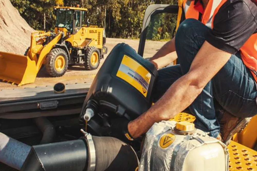 Um homem usando colete laranja e capacete amarelo realizando a manutenção em uma máquina SDLG